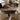 A handcrafted wooden coffee table made from black walnut with glossy resin inlay, positioned in a bright modern room with a window, window seat, and four gray chairs - BespokeTableCo