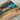 A resin table display featuring golden camphor wood with a turquoise blue resin river, showcased in a bright studio setting for interior design presentation - BespokeTableCo