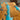Surface detail of a custom resin table capturing the striking contrast between the warm olive wood tones and the brilliant turquoise resin river - BespokeTableCo