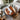 A round walnut coffee table with a white epoxy resin top and organic brown wood grain, surrounded by two woven wicker chairs in a bright modern kitchen-dining area with natural light - BespokeTableCo