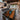 A large live-edge walnut wood dining table with a turquoise resin river flowing through the center, set in a bright modern open-plan kitchen and living room with large windows and warm natural light, featuring a premium natural wood table top - BespokeTableCo